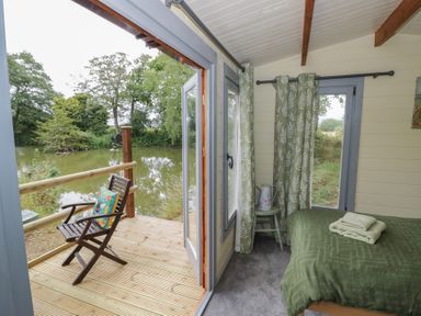 A bedroom with a bed and a chair at Carps Well Lodge in Hatton near Shrewley