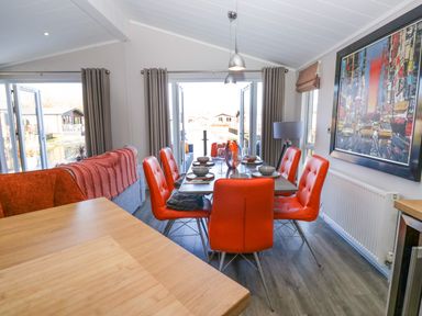 A dining area with orange chairs and a table set for a meal at Coniston View Lodge in Warton near Carnforth