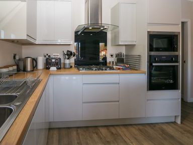 A kitchen with a gas stove microwave oven kettle and utensils at Coniston View Lodge in Warton near Carnforth