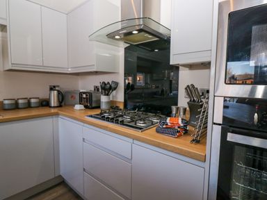 A kitchen with a gas stove, oven, toaster, kettle, utensils, and knife set at Coniston View Lodge in Warton near Carnforth
