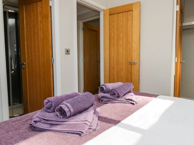 A bedroom with a bed covered with purple towels and wooden doors in the background at Coniston View Lodge in Warton near Carnforth