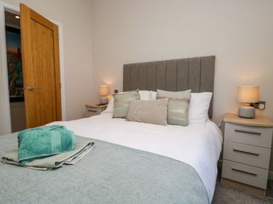A bedroom with a bed headboard pillows bedside tables and lamps at Coniston View Lodge in Warton near Carnforth