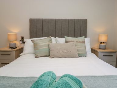 A bedroom with a bed with pillows and bedside tables with lamps at Coniston View Lodge in Warton near Carnforth