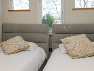 A bedroom with two beds with grey headboards and patterned pillows at Coniston View Lodge in Warton near Carnforth