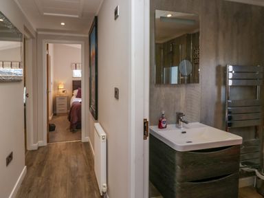 A hallway with a view into a bedroom and a bathroom with a sink and mirror at Coniston View Lodge in Warton near Carnforth