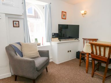 A living room with an armchair and television at Driftwood in Weymouth