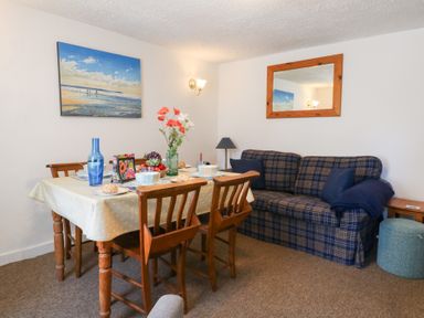 A dining room with a table and sofa at Driftwood in Weymouth