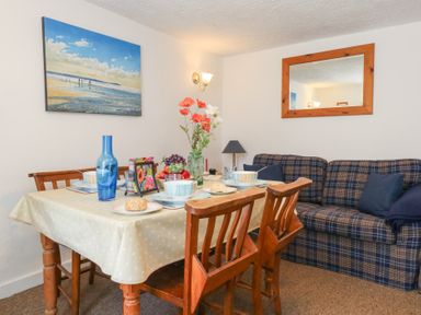 A dining room with a table set for meals at Driftwood in Weymouth