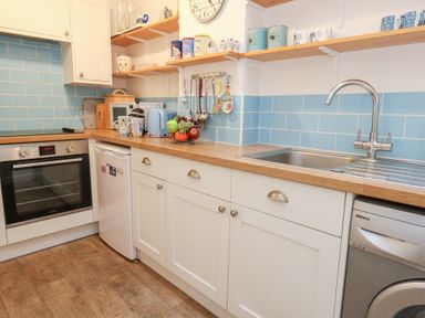 A kitchen with an oven, refrigerator, and sink at Driftwood in Weymouth