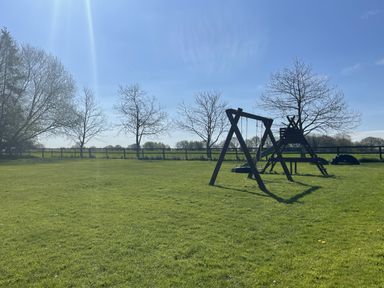 A swing set and slide on grass at Beechwood in Wood Norton near Foulsham