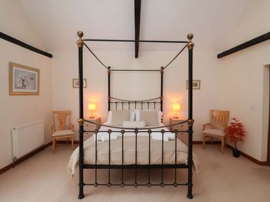 A bedroom with a four-poster bed and two chairs at Beechwood in Wood Norton
