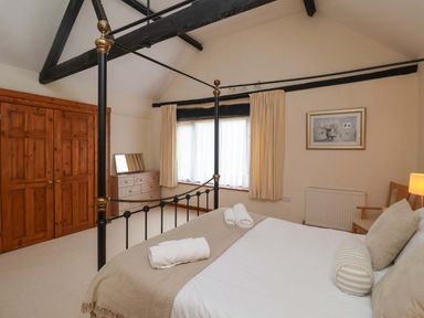 A bedroom with a four-poster bed and dresser at Beechwood in Wood Norton