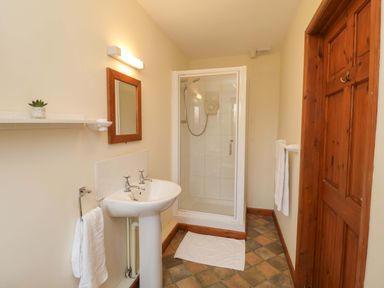 A bathroom with a sink, mirror, shower and towels at Beechwood in Wood Norton