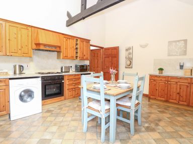 A kitchen with wooden cabinets and dining table at Willow in Wood Norton near Foulsham