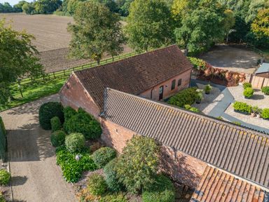 An outdoor view of a farmhouse with a garden and surrounding landscape at Willow in Wood Norton near Foulsham
