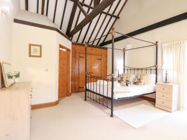 A bedroom with a four-poster bed and a dresser at Pear Tree in Wood Norton