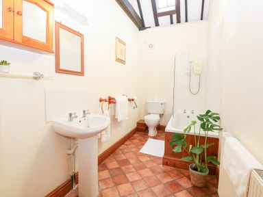 A bathroom with a bathtub and wash basin at Pear Tree in Wood Norton
