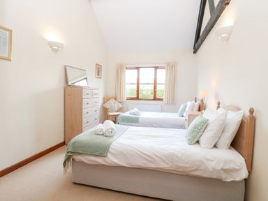 A bedroom with two beds and a dresser at Holly Berry in Wood Norton near Foulsham