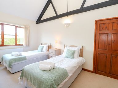 A bedroom with twin beds and a nightstand at Holly Berry in Wood Norton near Foulsham