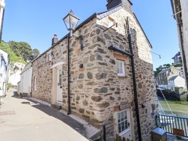 A narrow street with stone cottages and a lamp post by a waterfront at Harbour View in Polperro