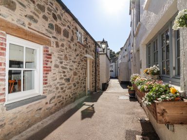 A narrow street with stone and white walls and flower boxes on windowsills at Harbour View in Polperro