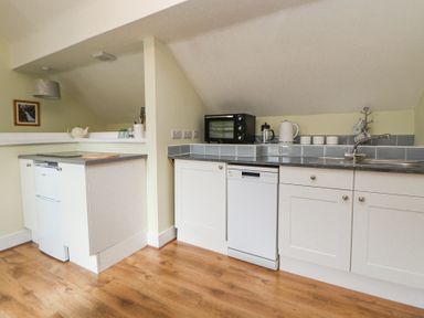 A kitchen with white cabinets a dishwasher a refrigerator an oven and a sink at Cuddfan at Swallow Cottage in Rhydtalog near Coedpoeth