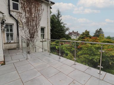 An outdoor patio with a railing and view of the garden at High Cross in Keswick