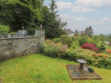A garden with a stone wall and seating at High Cross in Keswick