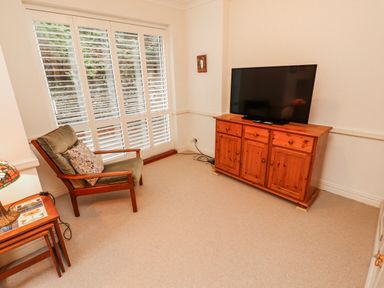 A living room with a television and an armchair at High Cross in Keswick