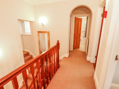 A hallway with a staircase and mirror at High Cross in Keswick