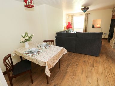 A dining area with a table and a couch at Dolcoed in Manordeilo near Llangadog
