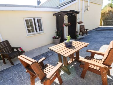 An outdoor seating area with wooden chairs and a table at Dolcoed in Manordeilo near Llangadog