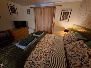 A bedroom with a bed, television, and a dressing table at Dolcoed in Llandeilo