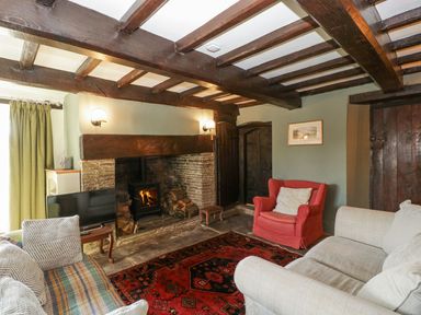 A living room with a wood-burning stove a red armchair and sofas at White Haywood Farmhouse & Barn in Craswall