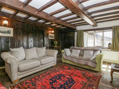 A living room with two sofas a red patterned rug and wooden ceiling beams at White Haywood Farmhouse amp Barn in Craswall