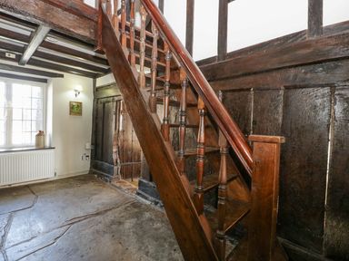 A wooden staircase with turned balusters in a room with exposed wooden beams and stone floor at White Haywood Farmhouse Barn Craswall