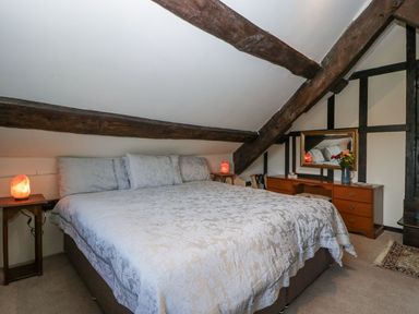 A bedroom with a large bed bedside tables with lamps and a dresser with a mirror at White Haywood Farmhouse & Barn in Craswall
