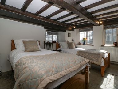 A bedroom with two single beds wooden beams on the ceiling and windows with flower vase at White Haywood Farmhouse & Barn Craswall