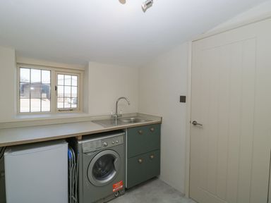 A utility room with a washing machine refrigerator and sink at White Haywood Farmhouse & Barn in Craswall