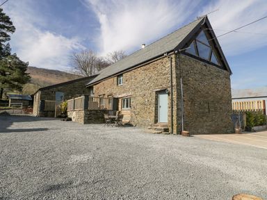 A stone farmhouse with gravel driveway and outdoor seating at White Haywood Farmhouse & Barn in Craswall