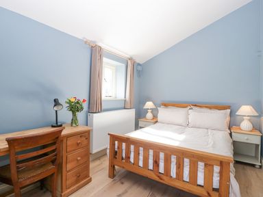 A bedroom with a wooden bed and desk with a chair and lamps at White Haywood Farmhouse & Barn in Craswall
