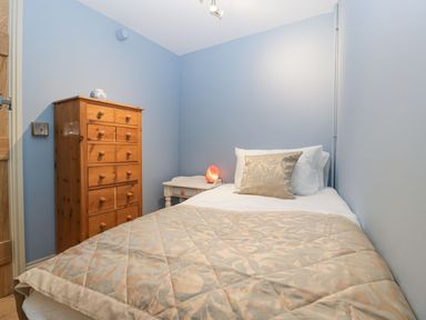 A small bedroom with a single bed a wooden chest of drawers and a nightstand with a lamp at White Haywood Farmhouse & Barn in Craswall