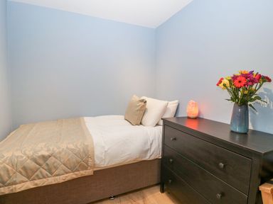 A bedroom with a single bed and a dark dresser with a vase of flowers and a lamp at White Haywood Farmhouse & Barn in Craswall