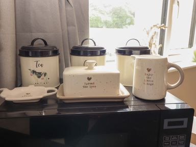 A kitchen countertop with tea canister, sugar canister, butter dish, and mug at O'Conells, Portmagee