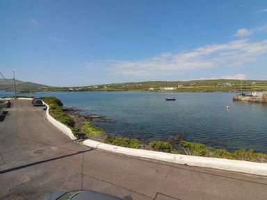 A view of the water and road with cars at O'Conells in Portmagee