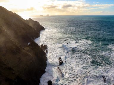 A coastal view showing cliffs, ocean waves, and distant islands at O'Conells in Portmagee