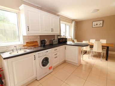 A kitchen with a washing machine and dining area at O'Connell's Lodge, Portmagee, County Kerry
