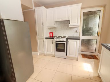 A kitchen with a fridge, oven, and cabinets at O'Connell's Lodge, Portmagee, County Kerry
