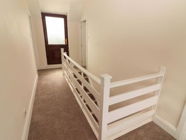 A hallway with a white railing and a door at O'Connell's Lodge, Portmagee, County Kerry