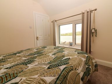A bedroom with a bed and window at O'Connell's Lodge in Portmagee, County Kerry